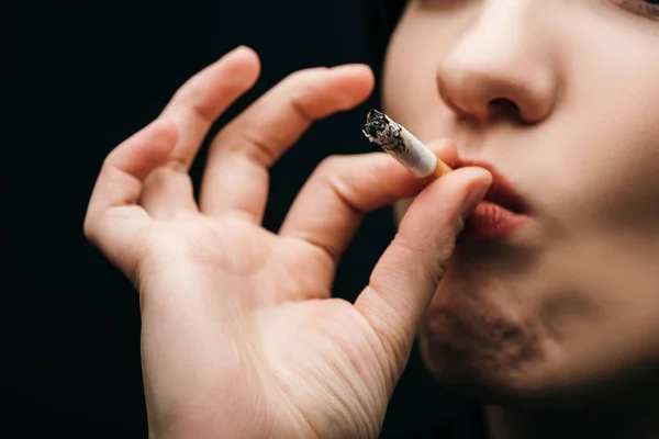 Vista recortada de la mujer fumando cigarrillo aislado en negro - foto de stock