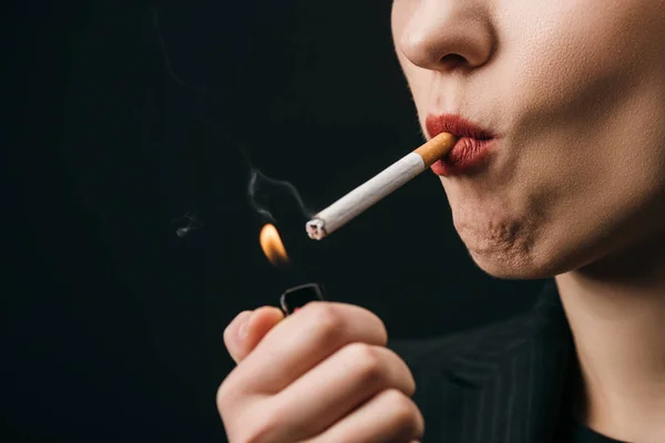 Vue recadrée de femme allumant cigarette avec briquet isolé sur noir — Photo de stock