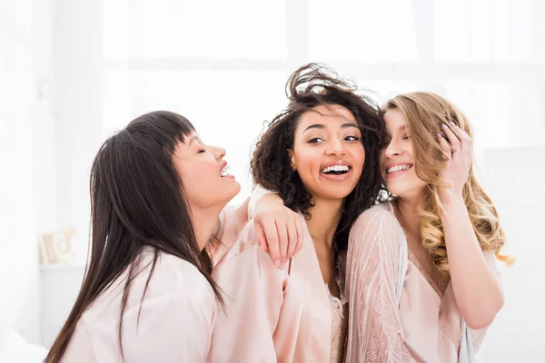 Happy multicultural girls in bathrobes hugging on bachelorette party — Stock Photo