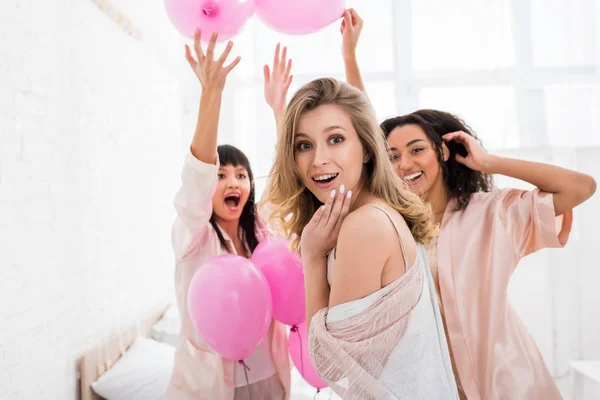 Meninas multiculturais animado se divertindo com balões rosa na festa de pijama — Fotografia de Stock