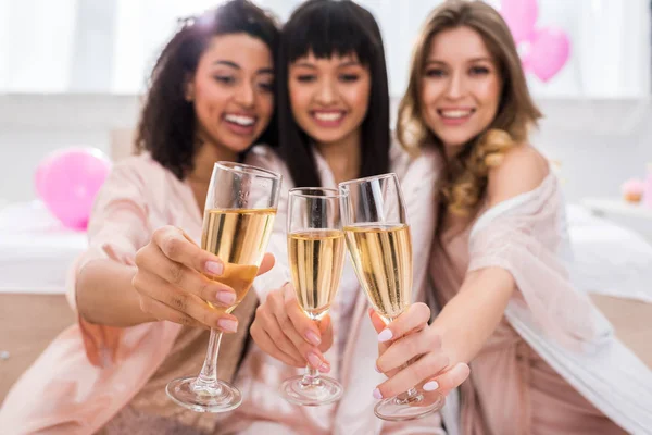 Fuoco selettivo di sorridente multiculturale ragazze clinking con bicchieri di champagne sulla festa di addio al nubilato — Foto stock