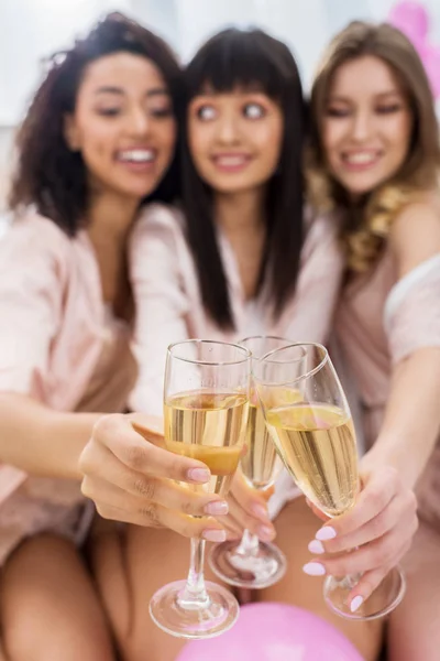 Selective focus of multicultural girls clinking with glasses of champagne on bachelorette party — Stock Photo