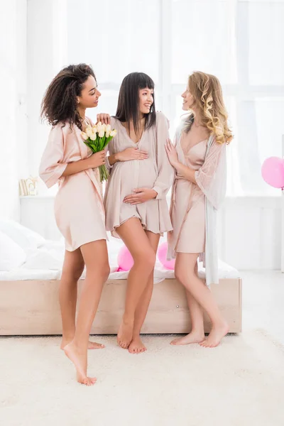 Feliz joven embarazada en baby shower con novias multiculturales - foto de stock