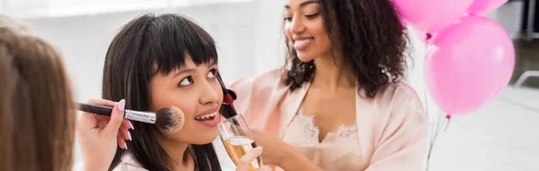 Colpo panoramico di ragazze multiculturali che applicano il trucco e bevono champagne all'addio al nubilato — Foto stock