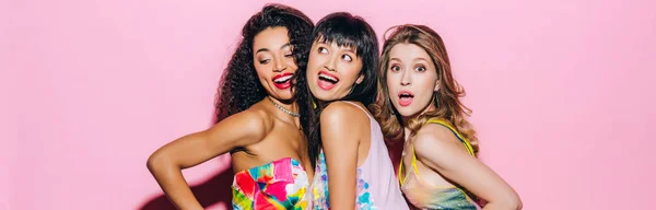 Panoramic shot of beautiful fashionable multicultural girlfriends posing on pink — Stock Photo