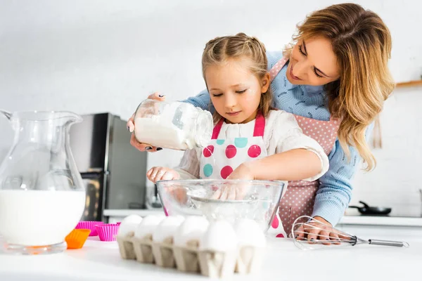 Mãe e filha peneirando massa para cupcakes através da peneira — Fotografia de Stock