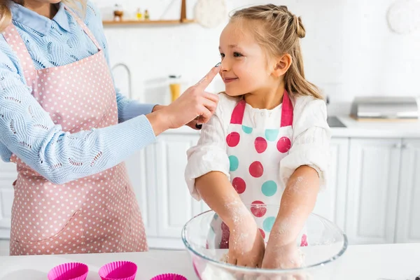 Mother touching nose of daughter during cooking in kitchen — Stock Photo