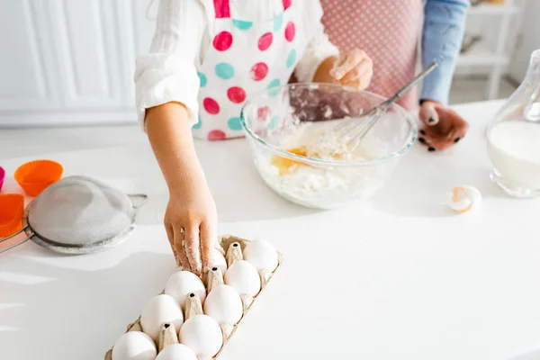 Selektiver Fokus der Kinderhand, die Ei für Teig in der Küche nimmt — Stockfoto