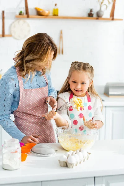 Mère regardant fille mignonne et choquée avec ballon fouet — Photo de stock