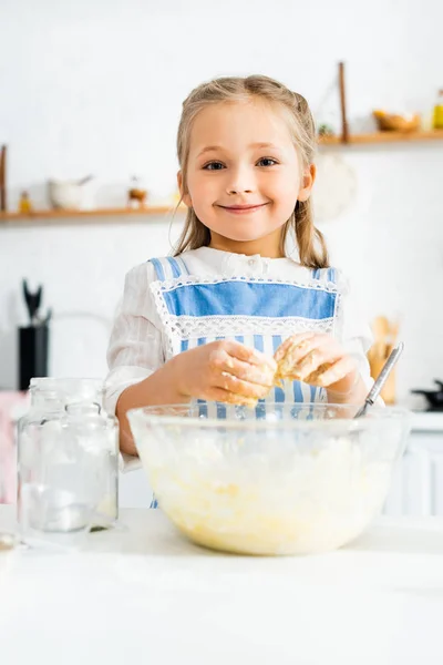 Bambino sorridente e carino in grembiule cottura pasta in cucina — Foto stock