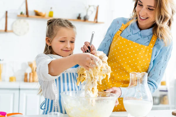 Cropped view of smiling mother and daughter cooking dough — Stock Photo