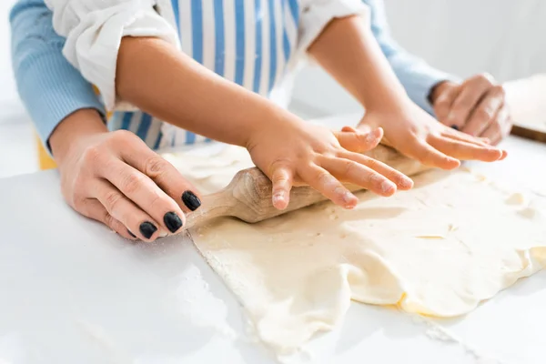 Cropped view of mother and daughter rolling dough on table — Stock Photo