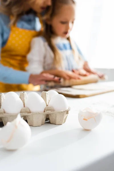 Selective focus of eggs in carton box and egg shells on table — Stock Photo