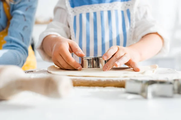 Enfoque selectivo del niño usando molde de masa en la masa en la cocina - foto de stock