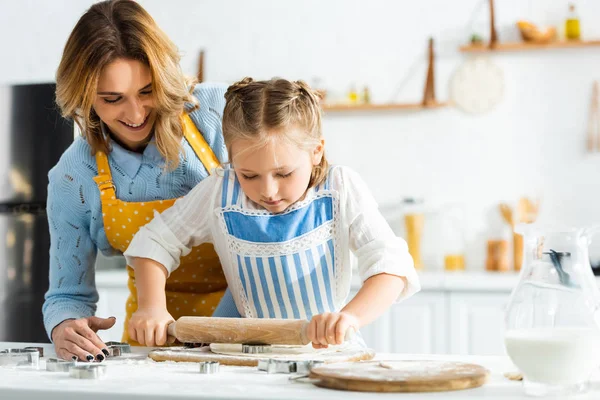 Улыбающиеся мать и дочь приготовления пищи со скалкой на кухне — стоковое фото