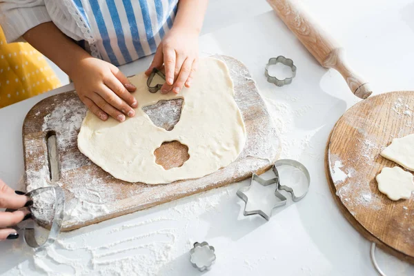 Vista recortada de galletas de cocina hija con moldes de masa - foto de stock