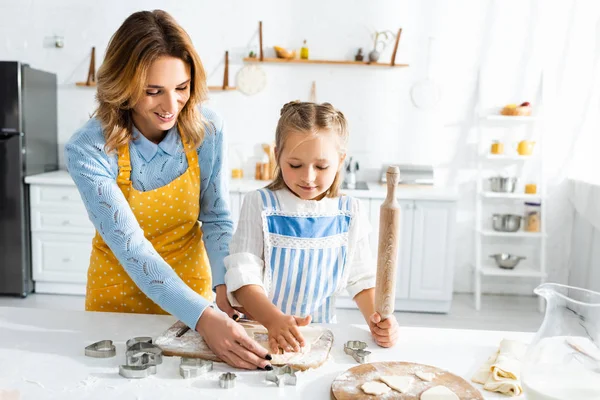 Sonriente madre y linda hija cocinar galletas en la cocina - foto de stock