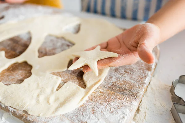 Cropped view of kid holding star-shaped dough in kitchen — Stock Photo