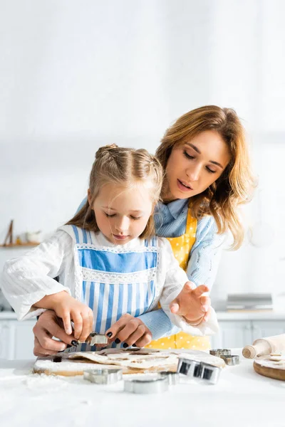 Attractive mother and cute daughter cooking cookies with dough molds — Stock Photo