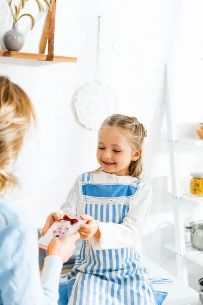 Figlia sorridente che presenta la carta a madre in giorno delle donne internazionale — Foto stock