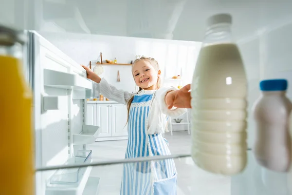 Selektiver Fokus des lächelnden Kindes, das Flasche mit Milch aus Kühlschrank nimmt — Stockfoto