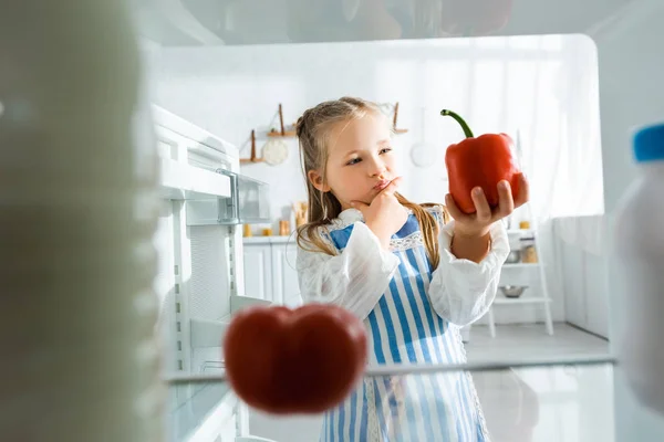 Selective focus of pensive kid looking at bell pepper — Stock Photo