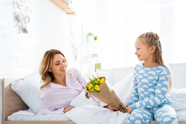 Smiling daughter presenting bouquet to mother in mothers day — Stock Photo