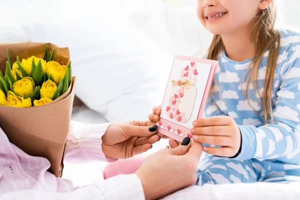 Cropped view of smiling daughter giving card to mother in international womens day — Stock Photo