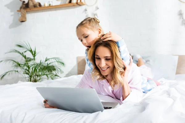 Sorridente mãe e filha olhando para laptop no quarto — Fotografia de Stock