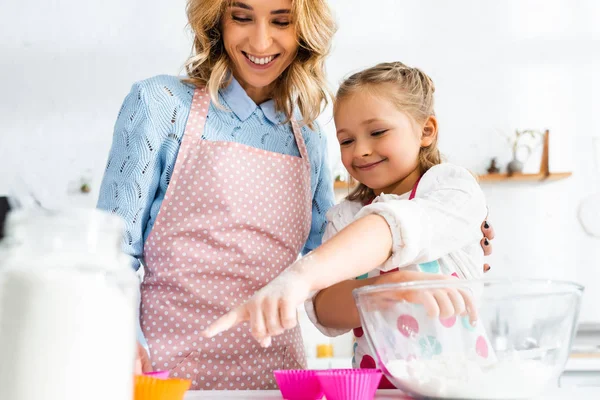 Vue à angle bas de la mère et de la fille souriantes pointant du doigt le moule à pâte — Photo de stock