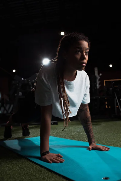 Afrikanerin steht in Planke auf Fitnessmatte im Fitnessstudio — Stockfoto