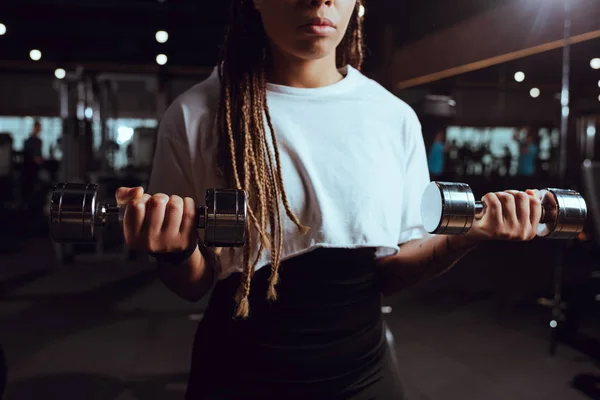 Cropped view of african american woman lifting dumbbells — Stock Photo