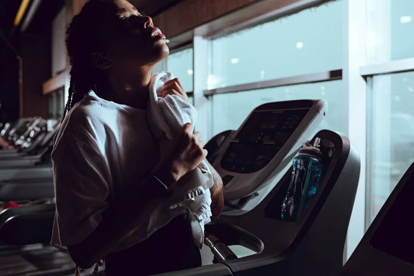 Attractive african american woman using towel after runnin on treadmill — Stock Photo