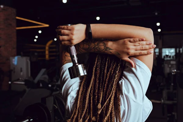 Vista posterior de una mujer afroamericana sosteniendo una mancuerna - foto de stock