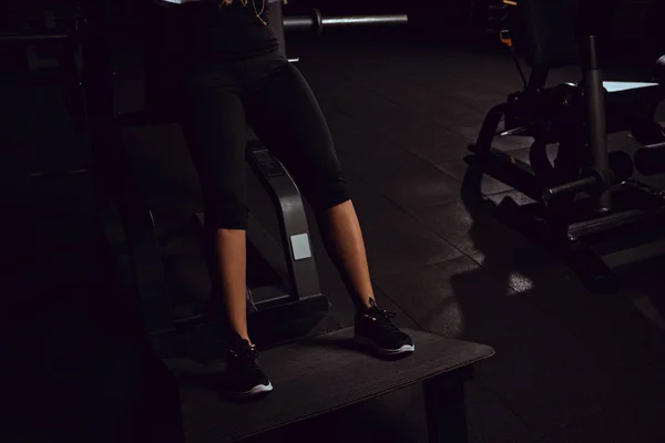 Vista recortada de chica afroamericana haciendo ejercicio en la máquina de gimnasio - foto de stock