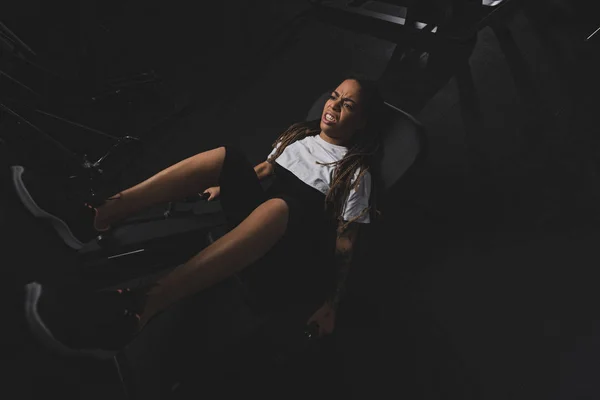 Vista aérea de la chica afro-americana emocional haciendo ejercicio en la máquina de gimnasio - foto de stock