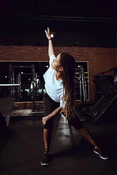 African american woman with dreadlocks stretching in gym — Stock Photo