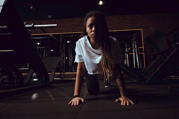 Mulher americana africana atraente com dreadlocks fazendo exercício prancha no ginásio — Fotografia de Stock