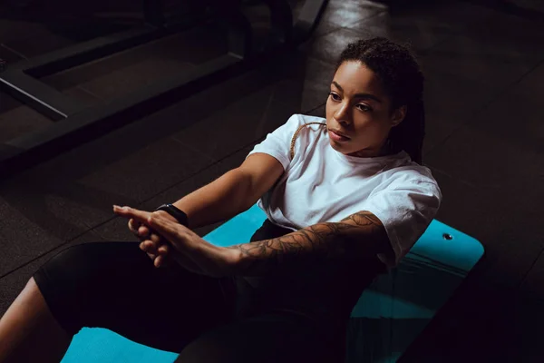 Tattooed african american woman doing exercise on fitness mat — Stock Photo