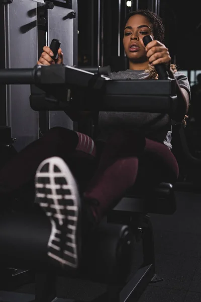 Foyer sélectif de fille afro-américaine travaillant sur la machine de gymnase — Photo de stock