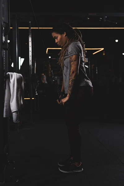 Side view of attractive african american girl with tattoo exercising in gym — Stock Photo