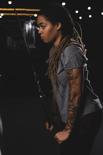 Side view of african american girl with tattoo exercising in gym — Stock Photo