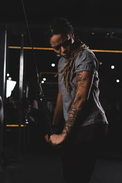 Young african american woman with tattoo exercising in gym — Stock Photo