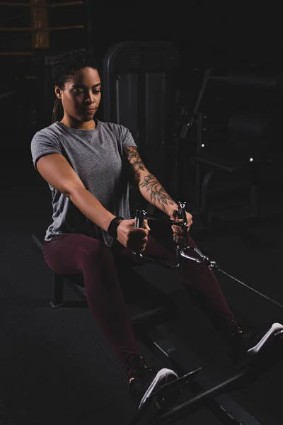 Sportive africaine américaine sportive avec tatouage faisant de l'exercice dans la salle de gym — Photo de stock