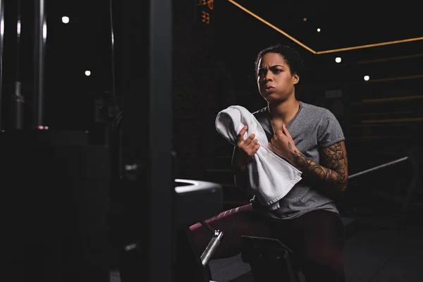 Selective focus of tired african american girl with tattoo holding towel — Stock Photo