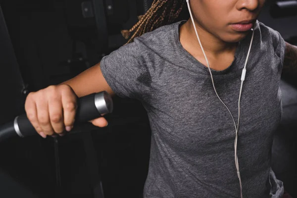 Cropped view of african american woman listening music while exercising in gym — Stock Photo