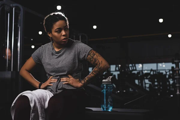 Femme afro-américaine tatouée avec les mains sur les hanches dans la salle de gym — Photo de stock