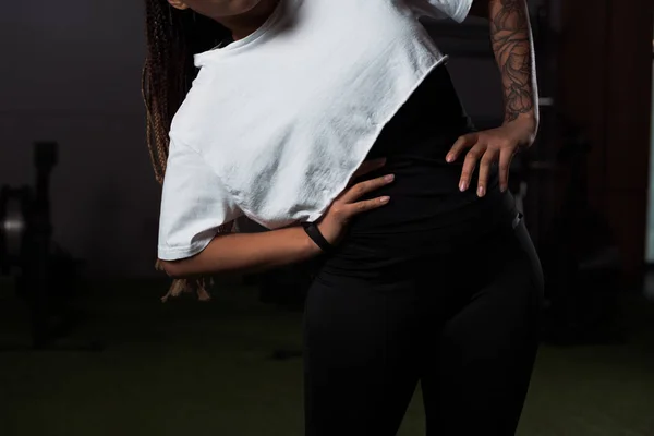 Cropped view of tattooed african american woman with hands on hips exercising in gym — Stock Photo