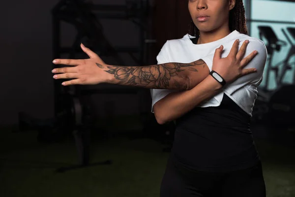 Abgeschnittene Ansicht tätowierter afrikanisch-amerikanischer Frau, die im Fitnessstudio trainiert — Stockfoto