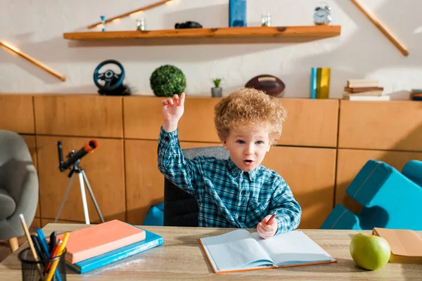 Lindo e inteligente niño con la mano levantada en casa - foto de stock